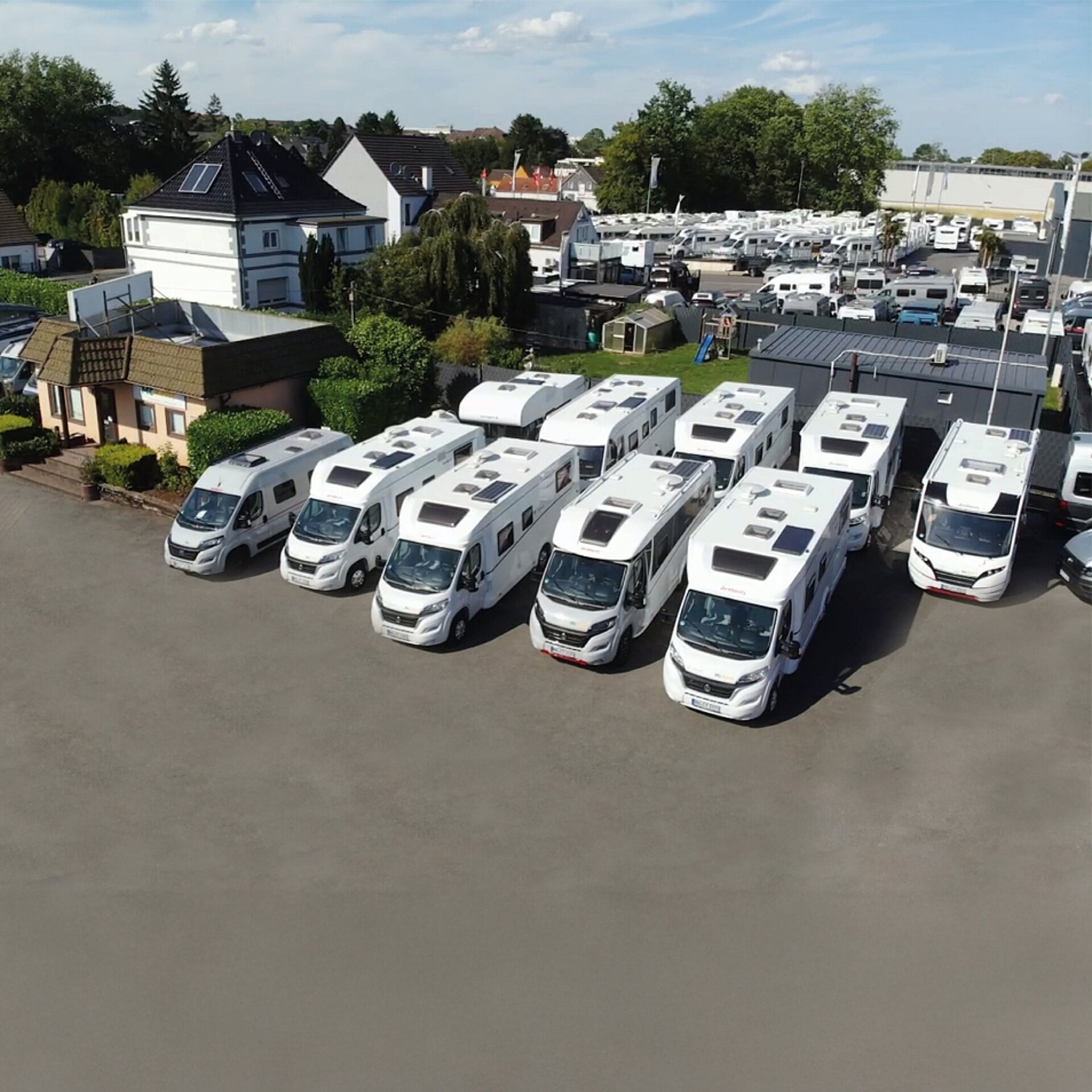 Blick auf einen Parkplatz mit vielen Wohnmobilen in einer Reihe.
